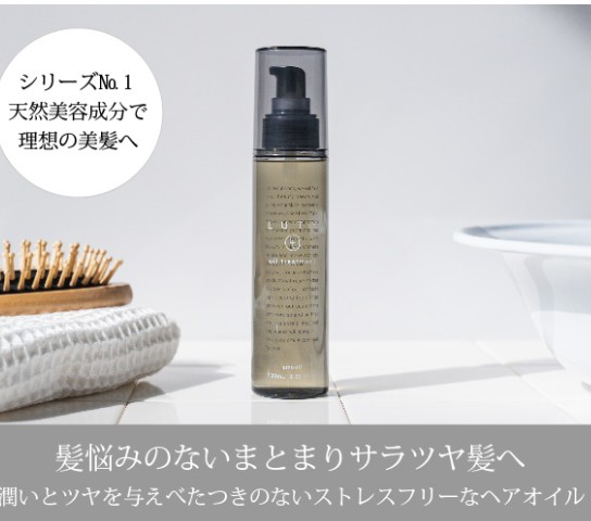 Bottle of hair oil with a pump on a white bathroom counter; circular Japanese label promotes natural beauty ingredients.